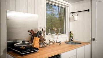 A kitchen with a wooden countertop, stainless steel appliances, and a window with a view of trees.