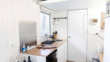 A compact kitchen with a wooden countertop, a sink, and a dishwasher.