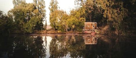 Una casa flotante en un lago tranquilo rodeado de árboles.