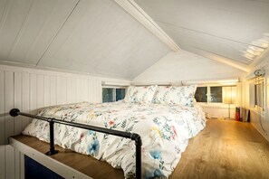 Une chambre à coucher avec un lit, une fenêtre et un plancher en bois.