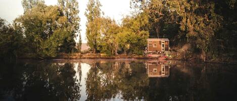 A houseboat on a calm lake surrounded by trees.