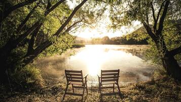 Two wooden benches facing a calm lake with trees on either side.