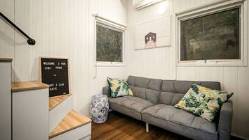 A cozy room with a grey sofa, wooden steps, a small table, and a decorative lamp.