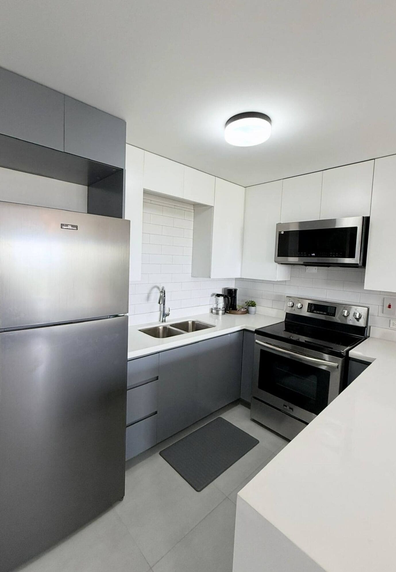 Una cocina moderna con electrodomésticos de acero inoxidable, armarios blancos y un microondas integrado.