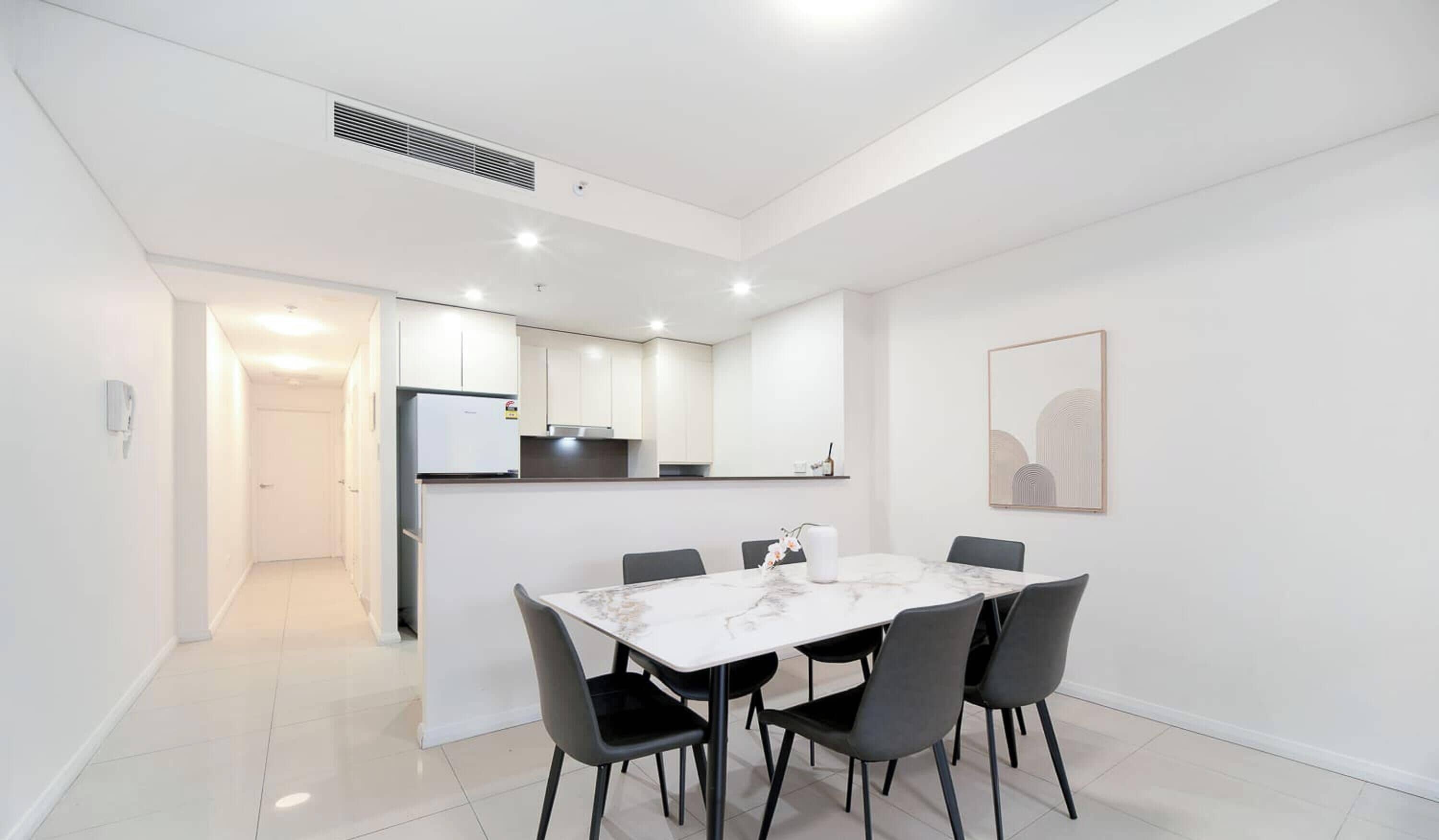 A modern kitchen with white cabinets and a built-in refrigerator.