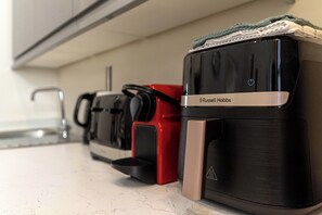 Una cocina con una cafetera, un electrodoméstico rojo y un electrodoméstico negro con una etiqueta.