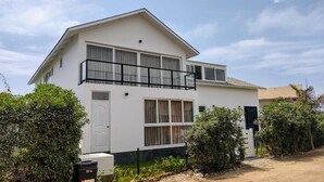 Un edificio residencial de dos pisos con balcón, puerta principal y puerta de garage.