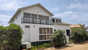 A two-story residential building with a balcony, a front door, and a garage door.