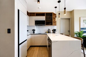 A modern kitchen with a central island, built-in microwave, and wooden shelving. - w Chic 2BR w Balcony AC in San Francisco (Panama City)