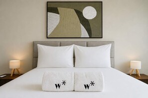 A hotel room with a large bed, two bedside lamps, and a framed abstract painting above the bed. - w Chic 2BR w Balcony AC in San Francisco (Panama City)