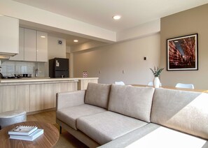 A modern living space with a sofa, a dining table, and a kitchen area. - w Airy 2BR w Balcony in Prime Miraflores (Lima)