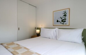 Ein Hotelzimmer mit einem Bett, einem Nachttisch, einer Lampe und einem gerahmten Bild an der Wand.