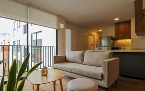 A modern apartment with a balcony, a sofa, a small table, and a kitchen area. - w Prime 2BR w Balcony in Miraflores (Lima)
