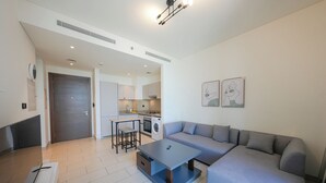 A modern living room with a grey sofa, a small table, and a kitchen area in the background. - Sobha Creek Vistas Reserve Tower A (Dubai)