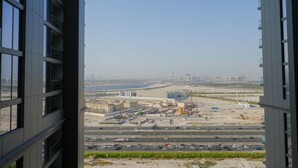 A view from a high-rise building overlooking a construction site with multiple buildings and a highway. - Sobha Creek Vistas Reserve Tower A (Dubai)