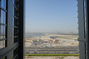 A view from a high-rise building overlooking a construction site with multiple buildings and a highway. - Sobha Creek Vistas Reserve Tower A (Dubai)