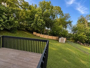 Une terrasse en bois donnant sur un jardin, une clôture en bois et un abri de jardin.