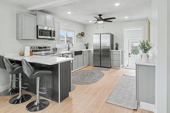 A modern kitchen with a central island, stainless steel appliances, and bar stools.