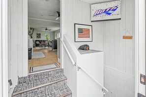 A staircase leading to a living area with a ceiling fan, a framed American flag, and a sign for 'Boo Motorsports'.