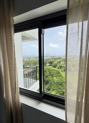 A window with a view of a balcony and a cityscape.