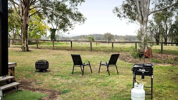 An outdoor seating area with two chairs, a picnic table, a grill, and a gas cylinder.