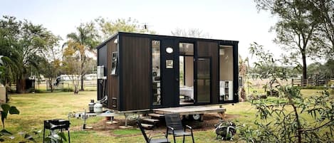 A modern, compact mobile home with a flat roof, large windows, and a small deck area.