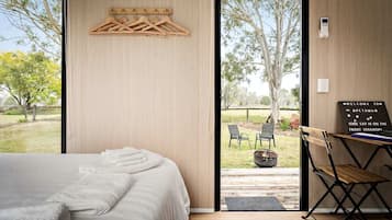 Un dormitorio moderno con una cama grande, un perchero de madera y un escritorio con una silla.