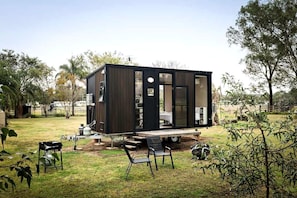 A modern, compact mobile home with a flat roof, large windows, and a small deck area.