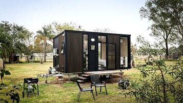 A modern, compact mobile home with a flat roof, large windows, and a small deck area.