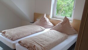 Uma cama de casal com cabeceira de madeira e janela com vista para árvores.