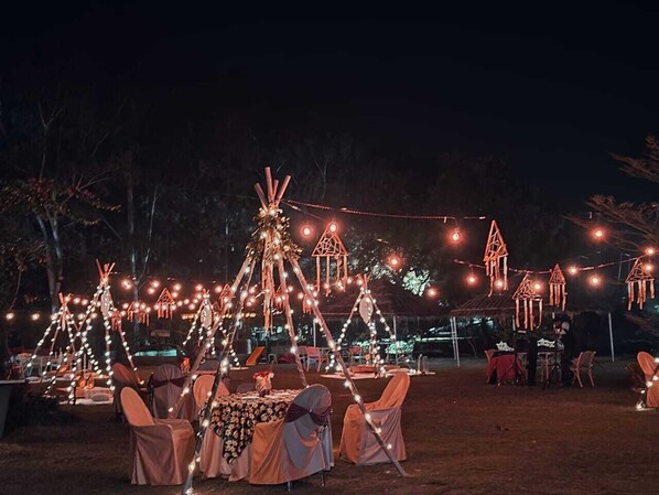 An outdoor event with illuminated structures and tables set up for an evening gathering.