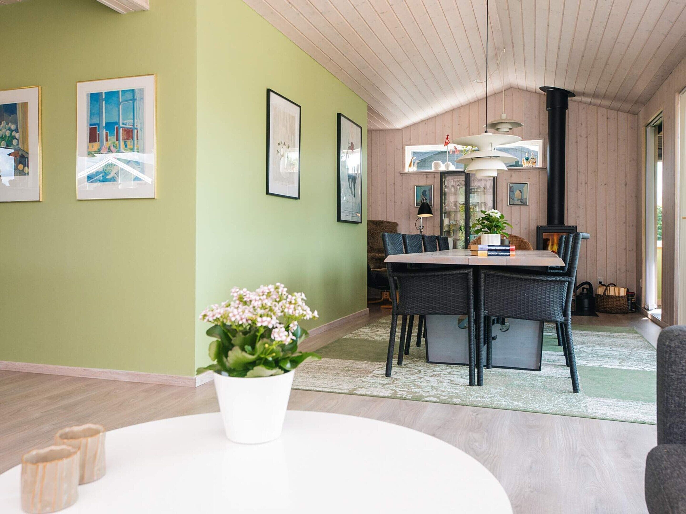 A dining area with a table and chairs, a potted plant, and framed artwork on the wall.