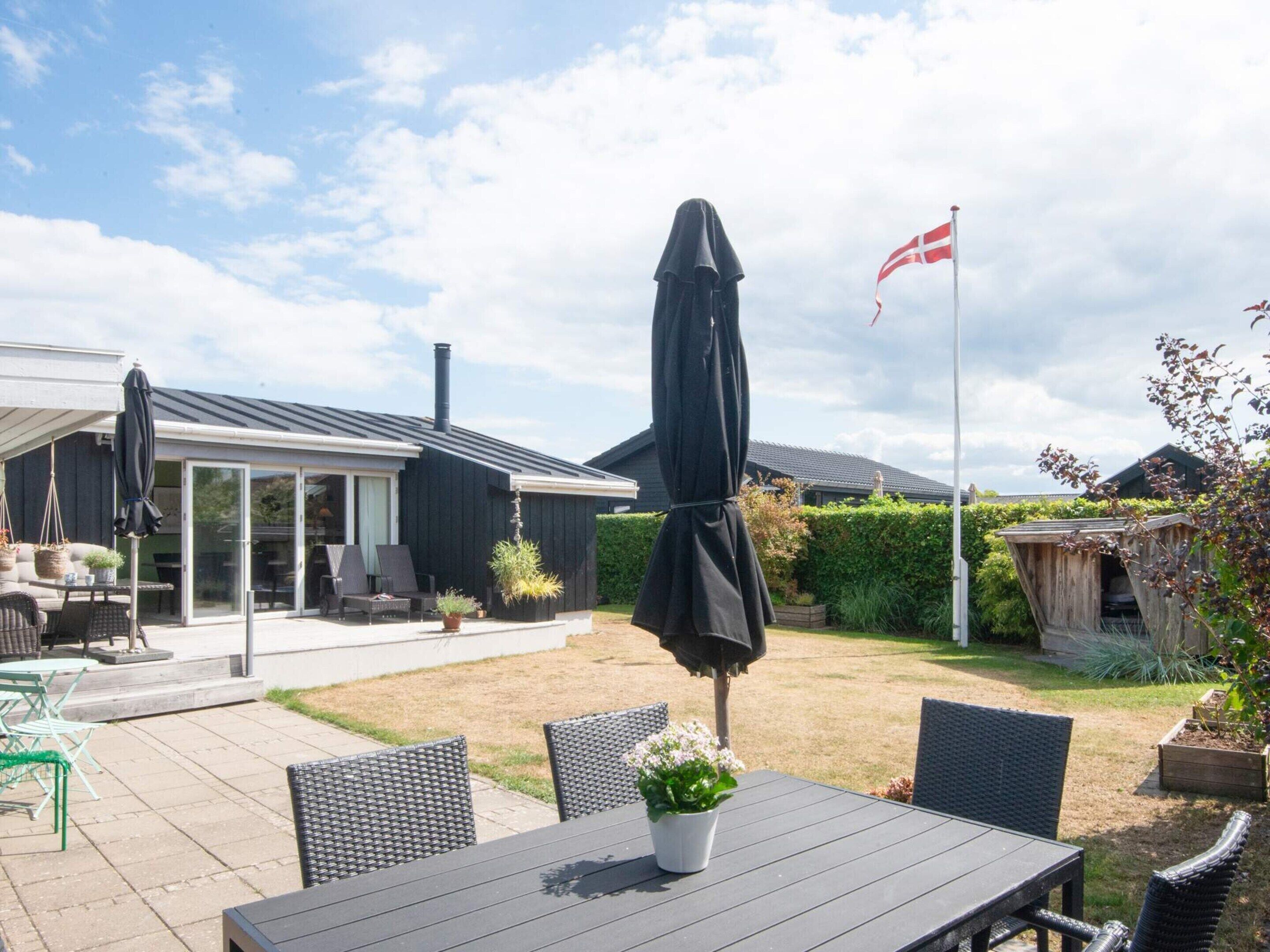 A patio area with outdoor furniture, a covered table, and a flag.