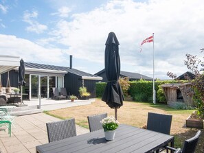 Eine Terrassenfläche mit Gartenmöbeln, einem überdachten Tisch und einer Flagge.