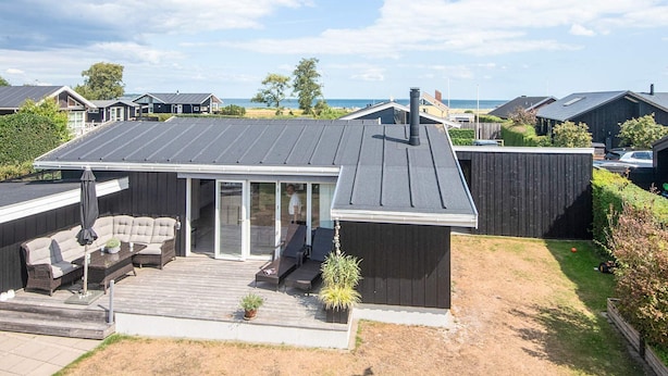 A residential property with a covered patio, outdoor seating, and a view of the sea. - 4 Star Holiday Home in Juelsminde (Juelsminde)