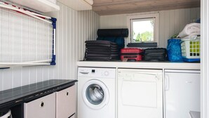 A compact laundry area with a washing machine, a dryer, and a window. - 4 Star Holiday Home in Juelsminde (Juelsminde)