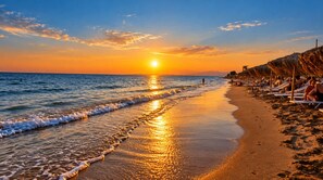 Une plage au coucher du soleil, avec des vagues et le soleil qui se reflète sur le sable.