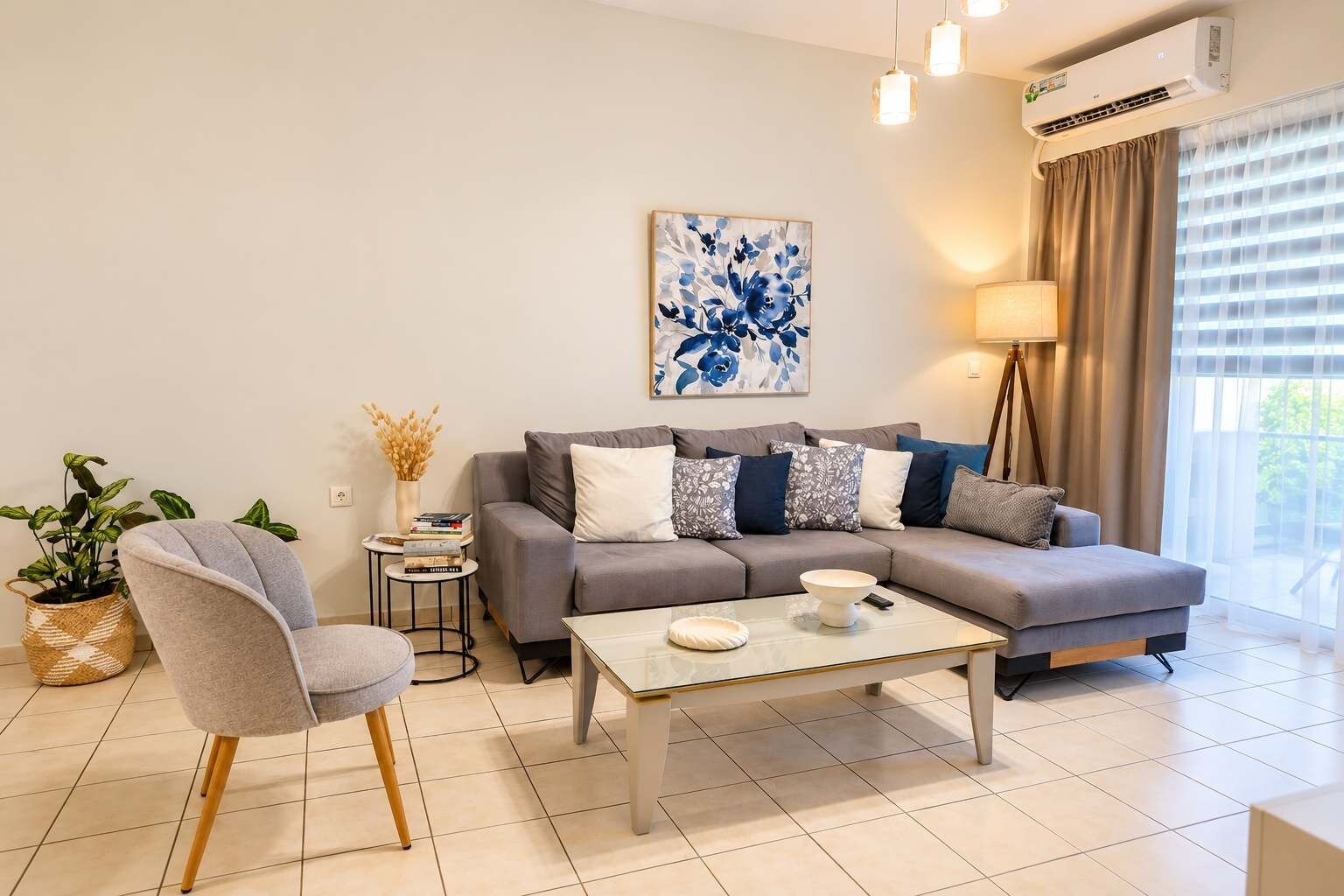 Ein modernes Wohnzimmer mit einem grauen Sofa, einem Couchtisch, einem Beistelltisch mit Pflanze und einem Bild an der Wand.