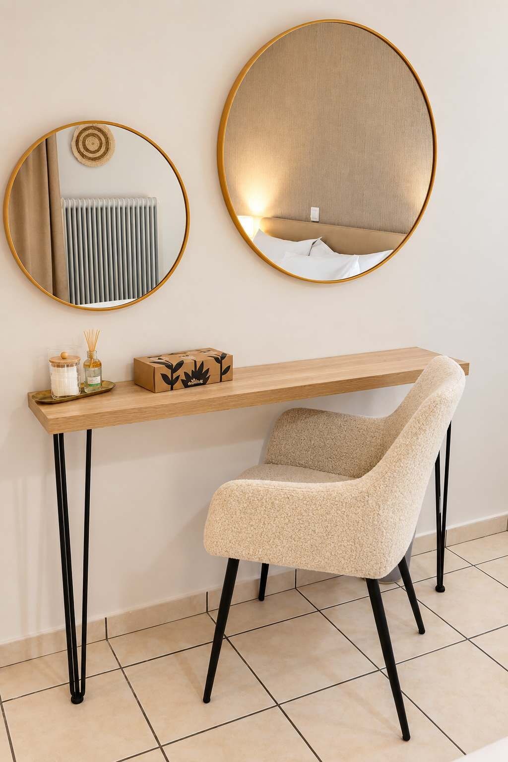 Une pièce avec un miroir rond, une console en bois, une chaise beige et un radiateur.