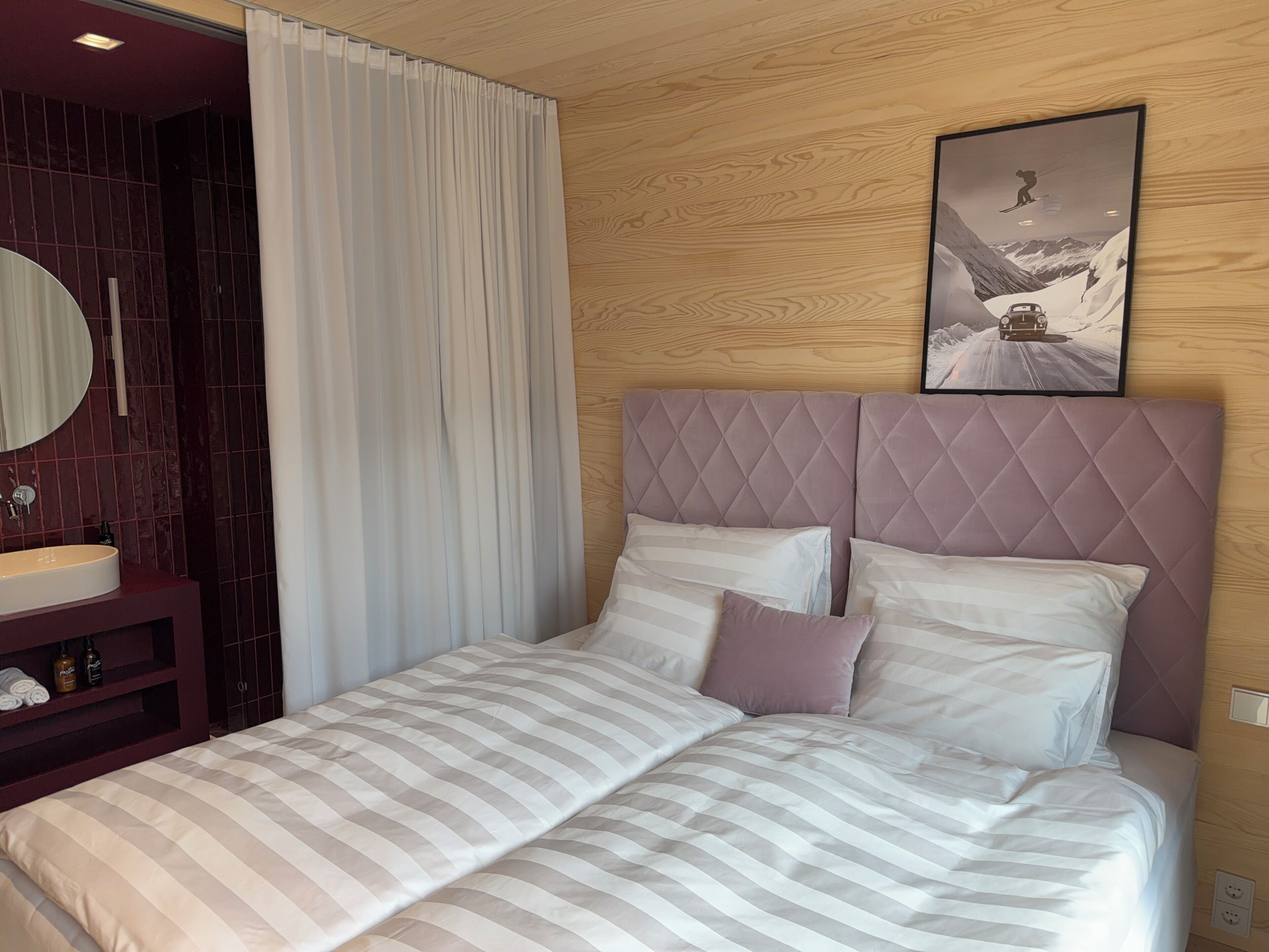 Ein Hotelzimmer mit Bett, Nachttisch, Spiegel und einem Bild an der Wand.