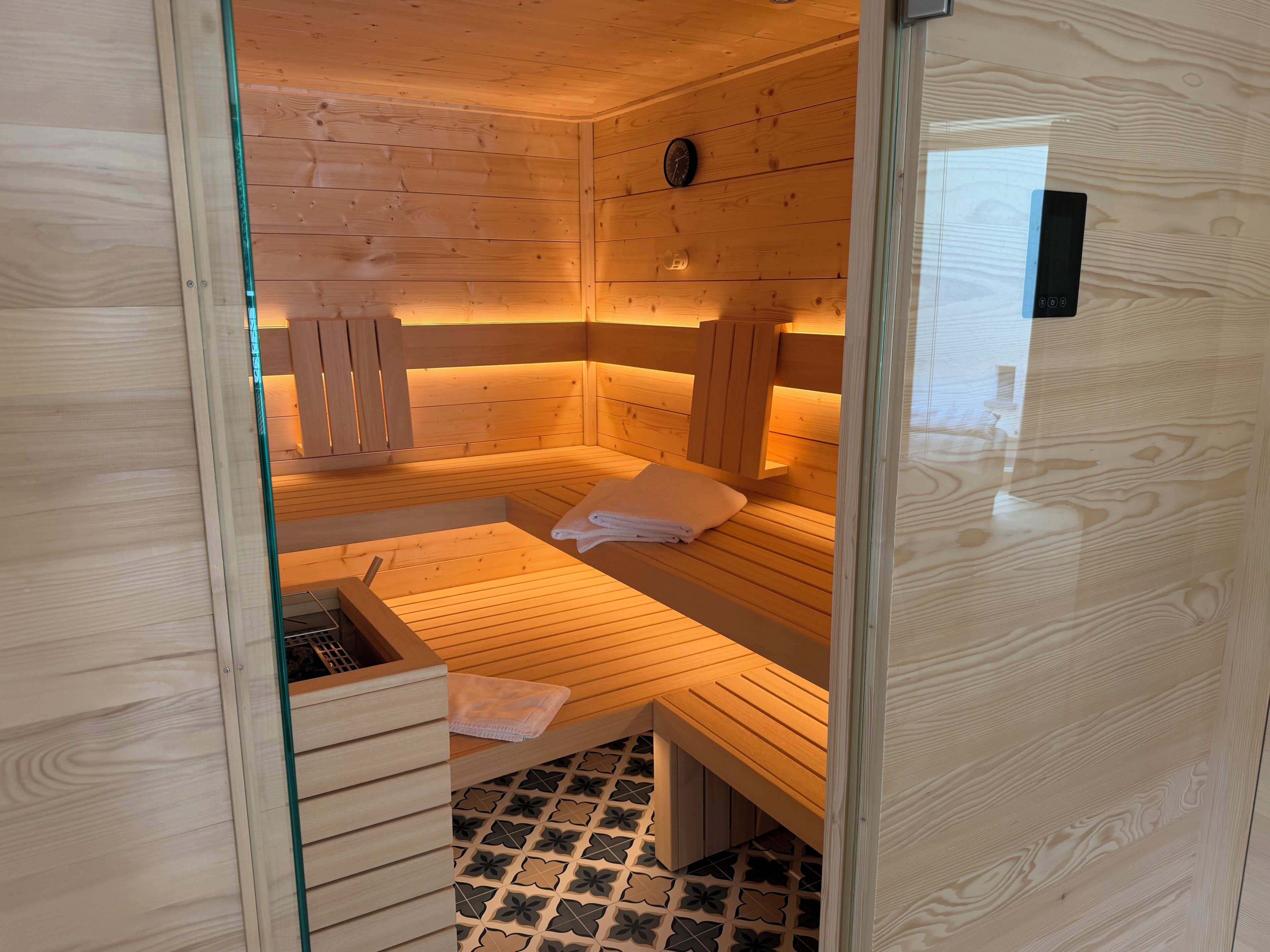 A sauna room with wooden benches and a glass door.