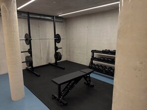 A gym with weightlifting equipment, a bench, and dumbbells.