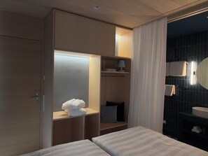 A hotel room with a bed, a wardrobe, a vanity with a mirror, and a bathroom with a sink and towel rack.