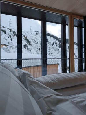Un dormitorio con un ventanal que da a un paisaje nevado de montañas.