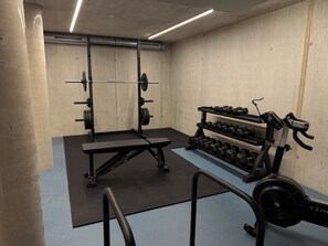 Uma academia com equipamentos de musculação, um banco e halteres.