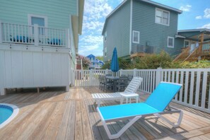 A wooden deck with a pool, lounge chairs, and a white fence. - Birdie Dunes | Private Pool | Walk to Beach | Holden Beach (Holden Beach)