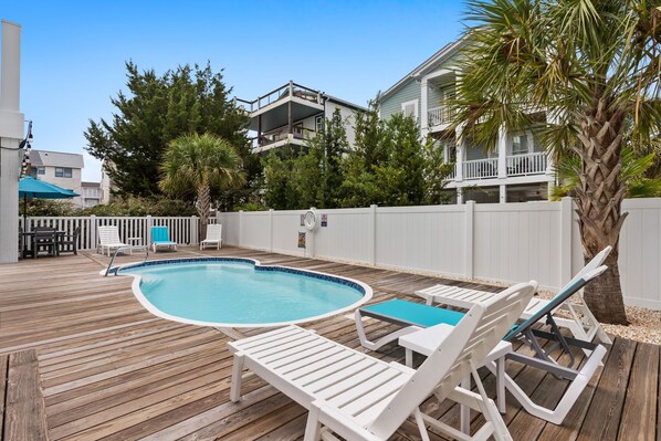 A swimming pool with lounge chairs and a wooden deck.