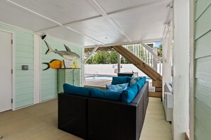 A covered outdoor seating area with a pool, a staircase, and a wall decorated with shark and fish cutouts.