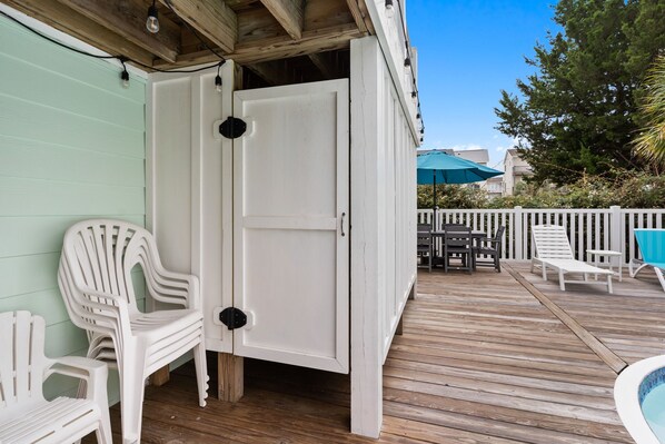 A wooden deck with a white door, outdoor furniture, and a pool.