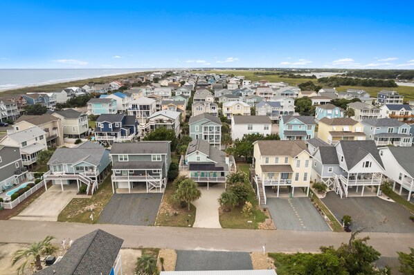 A residential area with houses, a clear sky, and a beach in the background.